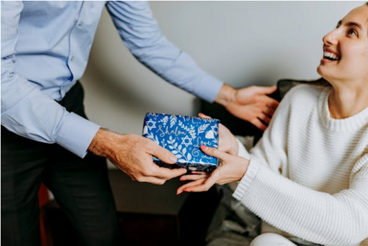 a man is giving a gift to a women and the women is so happy